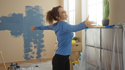 Woman painting indoors with blue paint in a home setting, exuding happiness and accomplishment,...