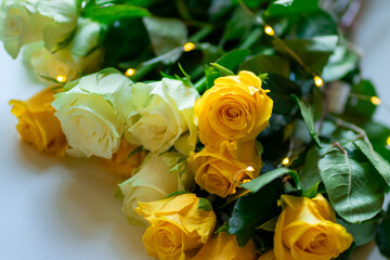 A bouquet of white and yellow roses lies on the table