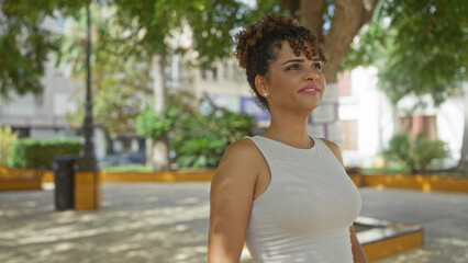 Woman enjoying the outdoors in a city park with a background of urban greenery on a sunny day.