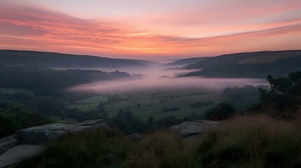 Obraz premium Scenic hilltop view overlooking a misty valley at sunrise, with soft pink and orange hues in the sky