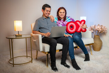 Comfortably seated, a couple engages with the digital world on their laptop, embracing togetherness and innovation.