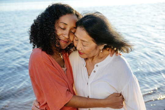Senior mother and adult daughter embracing with closed eyes
