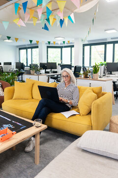 Senior Woman Focused On Laptop In Festive Office Setting