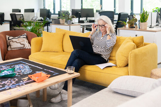 Senior Woman Adjusting Glasses While Working On Laptop