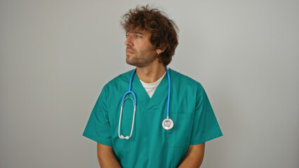 Young man in a medical uniform with a stethoscope over white background looking to the side, isolated, handsome and professional health worker portrait.