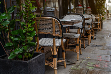 Quintessential Parisian café ambiance on a charming street in the 7th arrondissement. Elegant wicker chairs and wooden tables create an inviting scene perfect for dining, leisure, or urban lifestyle 