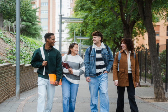 Happy College Students Discussing While Walking On Footpath