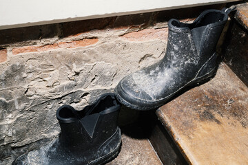 dusty black rubber boots on old wooden stairs