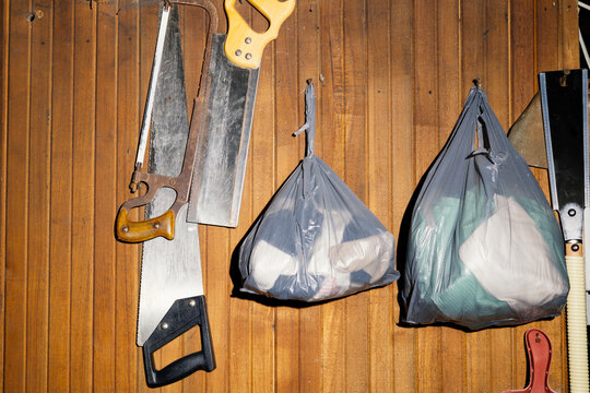 flash photograph of hand saws and plastic bags full of rags