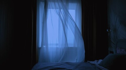 without people, empty dark room modern bedroom, white chiffon tulle fly, silk curtain fluttering waving from wind blow ventilation draft. Night twilight early morning dusk blue light. double bed made