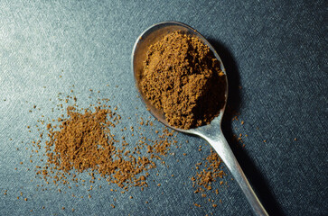 Spoon with ground natural coffee and lightly sprinkled on texture 