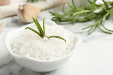 Sea salt, rosemary and garlic on white marble table, closeup