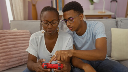 Mother and son sitting together in a cozy living room, bonding by playing a game on a console, showcasing their close family relationship and shared love for activities indoors