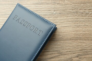 Passport in dark blue cover on wooden table, top view. Space for text