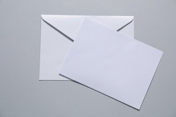 Paper envelope with letter on gray background, top view. Mockup for design
