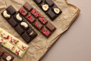 Different tasty chocolate bars on beige background, top view. Space for text