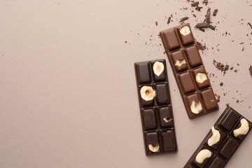 Tasty chocolate bars and crumbs on beige background, flat lay. Space for text