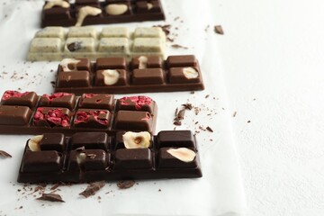 Tasty chocolate bars and crumbs on white textured background, closeup. Space for text