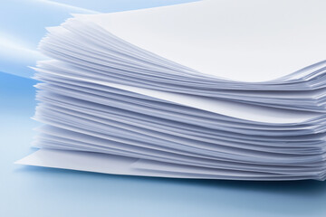 Stacked sheets of blank paper on a smooth blue surface in a well-lit environment