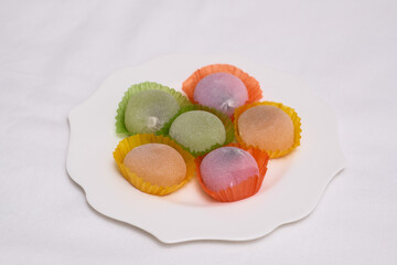 Delicious colorful mochi on white plate on light table, top view. Traditional Japanese dessert.