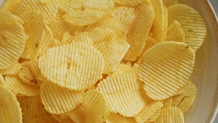 Closeup of crispy potato chips in a bowl showcasing the texture and golden color of the snack