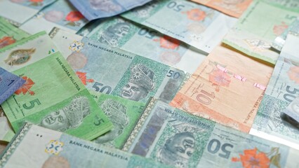 Malaysian banknotes depict various denominations of ringgit currency from bank negara malaysia scattered randomly.