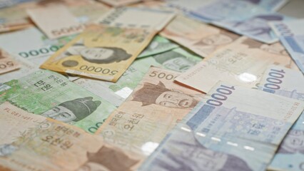 Scattered south korean won banknotes of various denominations, showcasing vibrant colors and detailed imagery.