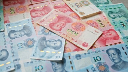 Obraz premium Chinese yuan banknotes scattered on a surface showcasing various denominations of currency from china.