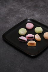 Delicious colorful mochi on black plate on dark background, top view. Traditional Japanese dessert.