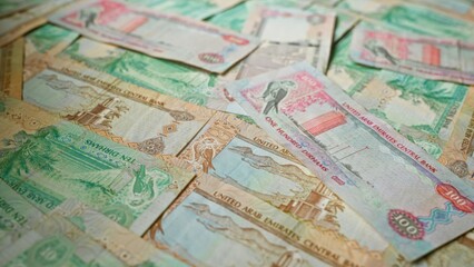 Fototapeta premium United arab emirates banknotes scattered, showcasing various denominations of uae dirhams, emphasizing wealth, finance, currency, and economic context.