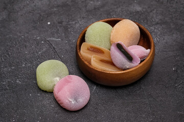 Delicious colorful mochi on wooden plate on dark background, top view. Traditional Japanese dessert.