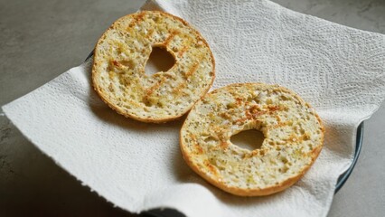 Two bagels on a paper towel placed on concrete surface