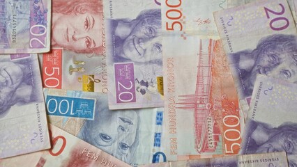 Swedish banknotes in various denominations of krona scattered on a flat surface showing vibrant...