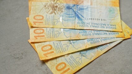 Naklejka premium Swiss banknotes scattered on a concrete surface, highlighting colorful ten franc notes from switzerland in a close-up shot.