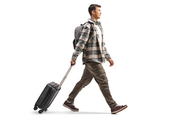 Full length profile shot of a student pulling a suitcase and walking