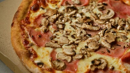 Delicious pizza with mushrooms and ham on a close-up view showing melted cheese and crispy crust