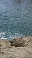 Ocean waves crashing against rocky coastline with a lone red buoy floating in the water on a clear day showcasing the natural beauty of the sea