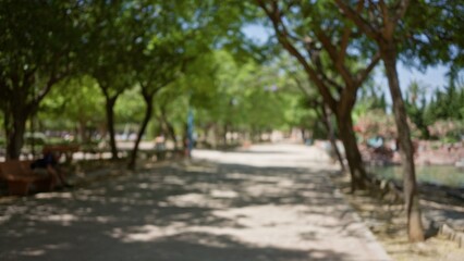 Outdoor park setting with blurred background, featuring defocused pathway, trees, benches, and a...