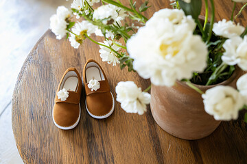baby announcement setting with handcrafted shoes, white flowers, vintage elements