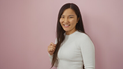Woman smiling isolated against a pink background depicting youthful style and cheerful demeanor...