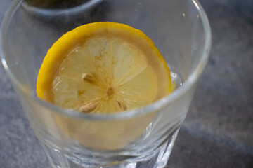 Fresh lemon slice in a glass with ice, refreshing drink concept