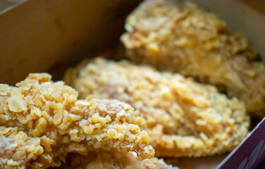 Delicious fried chicken pieces in a takeout box, showcasing crispy golden coating and mouthwatering texture