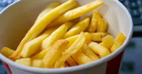 A close-up view of crispy golden French fries in a red and white cup, perfect for food lovers and fast-food enthusiasts.