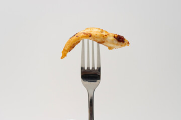 Piece of fried chicken skewered on a fork. Food close-up on white background, copy space