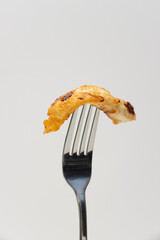 Piece of fried chicken skewered on a fork. Food close-up on white background, copy space