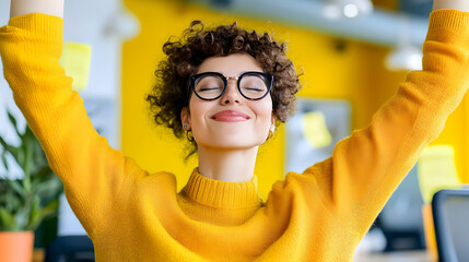 A woman with curly hair radiates happiness while enjoying a moment of triumph in a vibrant office