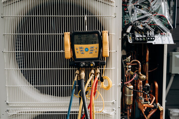 The service pressure gauge with colored hoses is connected to the air conditioning system. Copper...