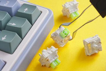 Computer keyboard switches and keycap puller on a bright yellow background. Repair, manufacturing...
