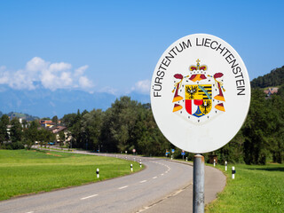 A road sign indicating the entrance to the Principality of Liechtenstein, featuring the coat of...