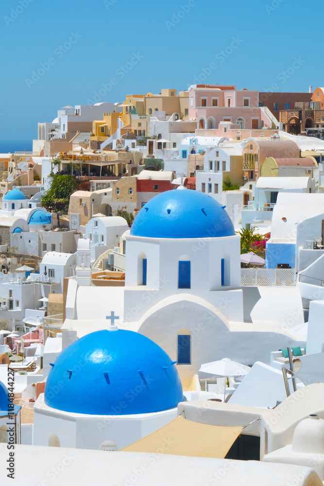 Wall mural Oia village on Santorini island, Greece. Traditional and famous houses and churches with blue domes over the Caldera, Cyclades islands Aegean sea.